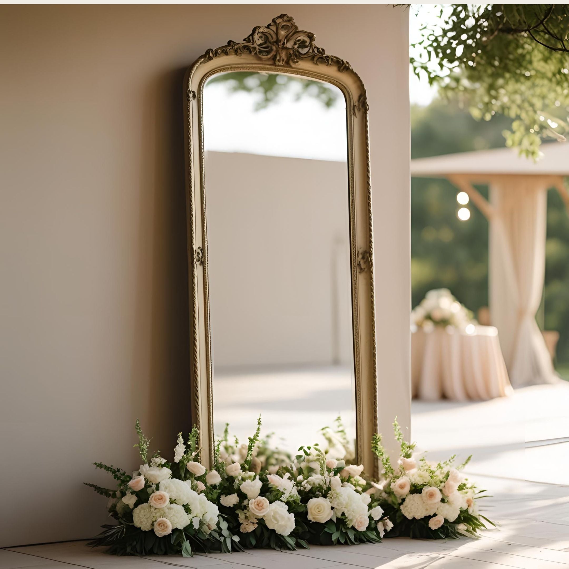 Decorative gold mirror with floral arrangement on a light wooden floor.